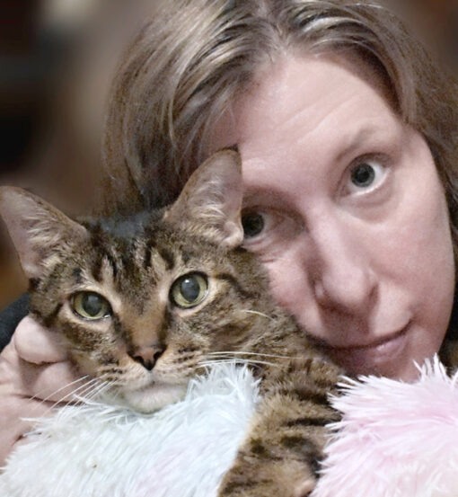 woman holding brown tabby cat