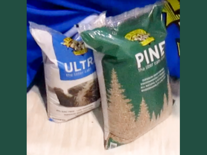 Two plastic bags of cat litter by Doctor Elsey’s. One has a blue label that says Ultra-Plus and the other has a green label that says Pine.