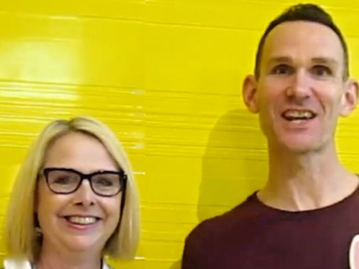 Blonde woman wearing glasses and taller man both smiling.