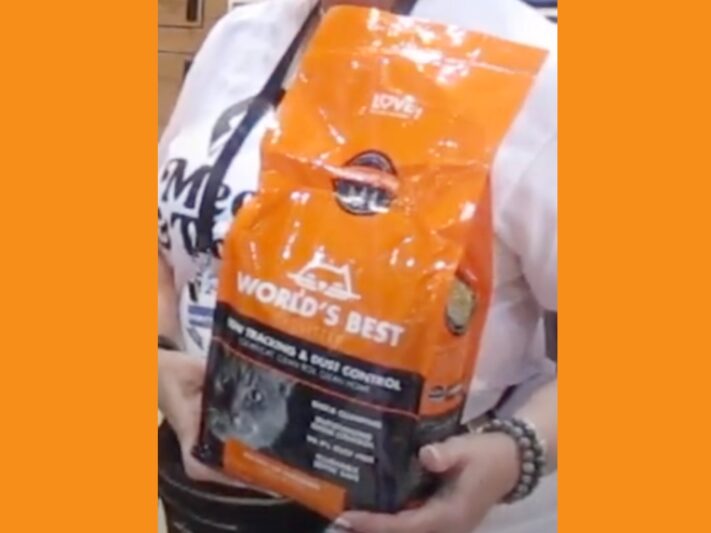 Woman holding an orange bag of World’s Best Cat Litter in the Low-Tracking and Dust Control variety.