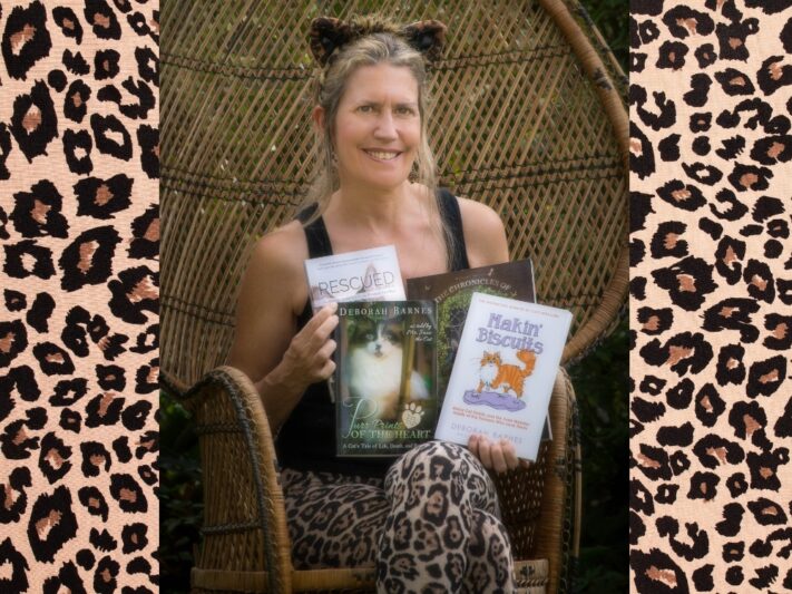 Deb in a peacock chair holding the four books she wrote.