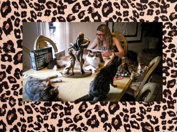 Deb Barnes working at a laptop surrounded by her cats.