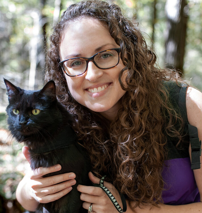 Emily Hall headshot - woman with black cat outside