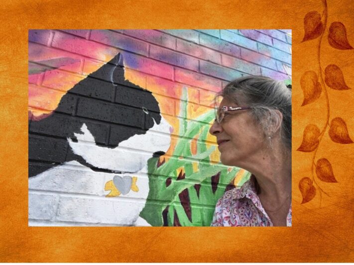 A woman looking at a mural painting of a cat.