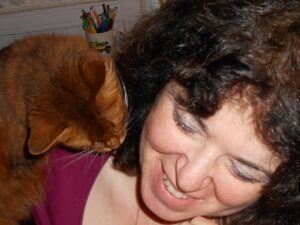 The author, a smiling woman with a cat looking over her shoulder.