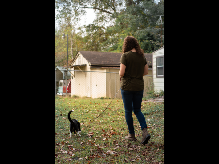 woman with cat otuside on harness and leash