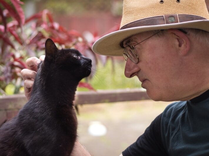 man and cat staring in each other's eyes