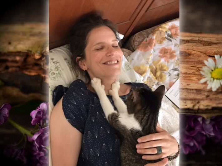 K Colitti - woman laying down on bed with cat on her chest